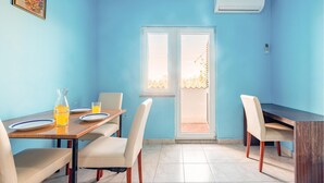 Un coin repas avec une table et des chaises, une fenêtre donnant sur un paysage agréable et un appareil de climatisation fixé au mur.