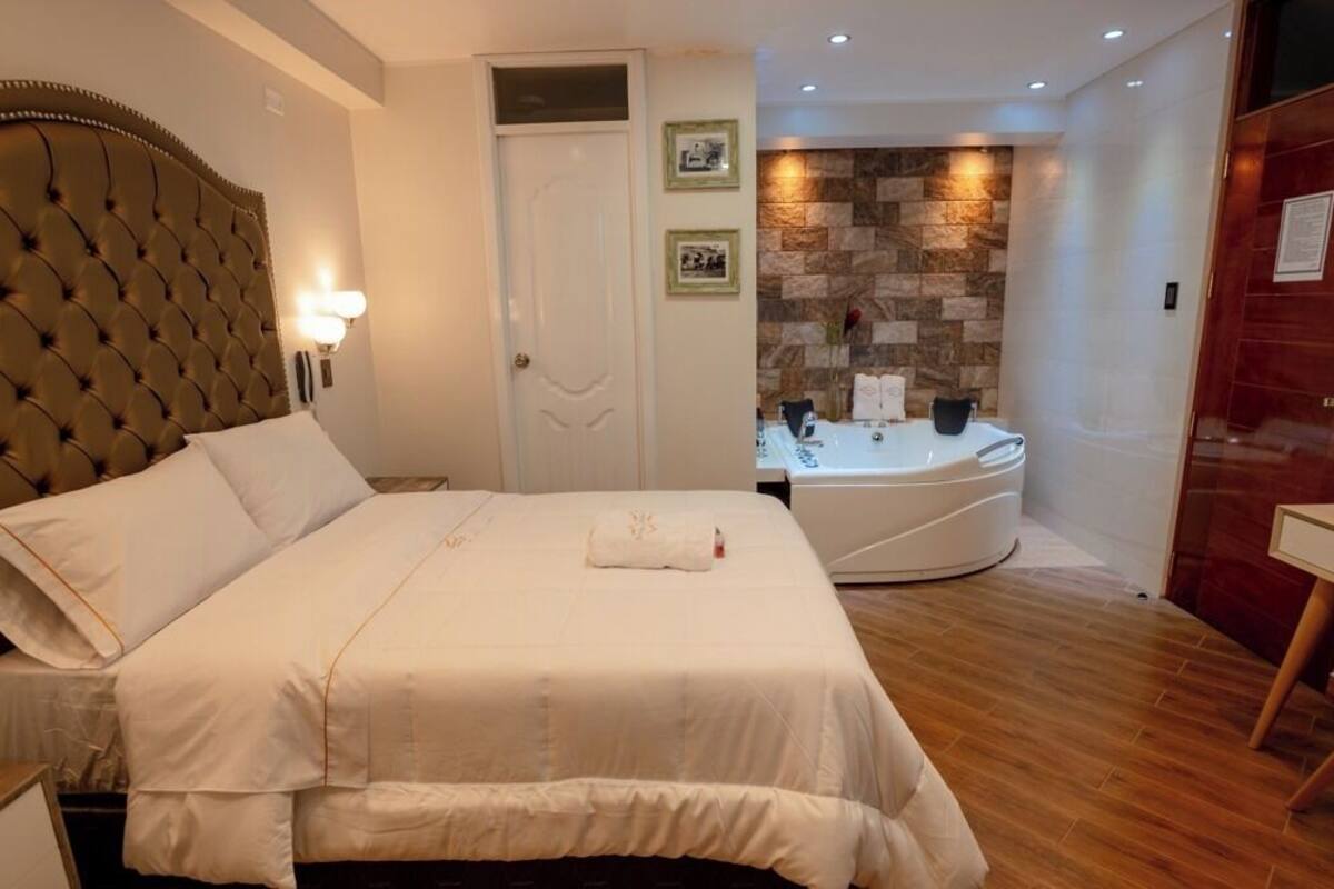 Ein Hotelzimmer mit einem großen Bett, einem Badezimmer mit einer Badewanne und einem kleinen Tisch.
