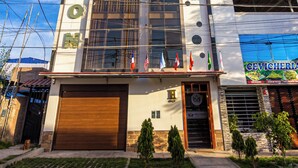 Un edificio moderno con un llamativo letrero de 'MELTHOM', un garaje y una tienda con la señalización 'CEVICHERA'.