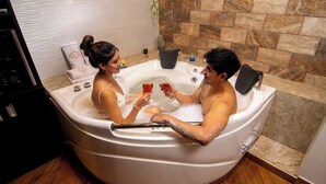 Una pareja en un jacuzzi con una pared de piedra y suelo de madera.