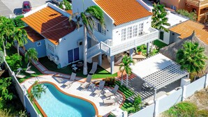 Une grande maison avec une piscine, plusieurs balcons et un jardin bien entretenu.