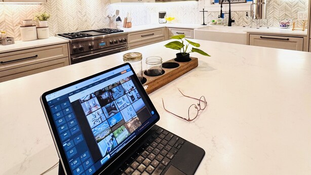 A modern kitchen with a laptop on the counter, wooden cabinets, and a herringbone-patterned backsplash. - Charming, Fully Restored 1.5 Story Farmhouse on Acreage (Muenster)