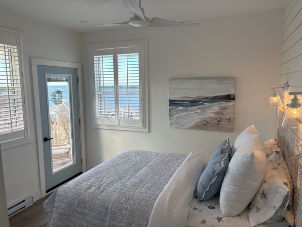 A bedroom with a bed, a door, and windows.