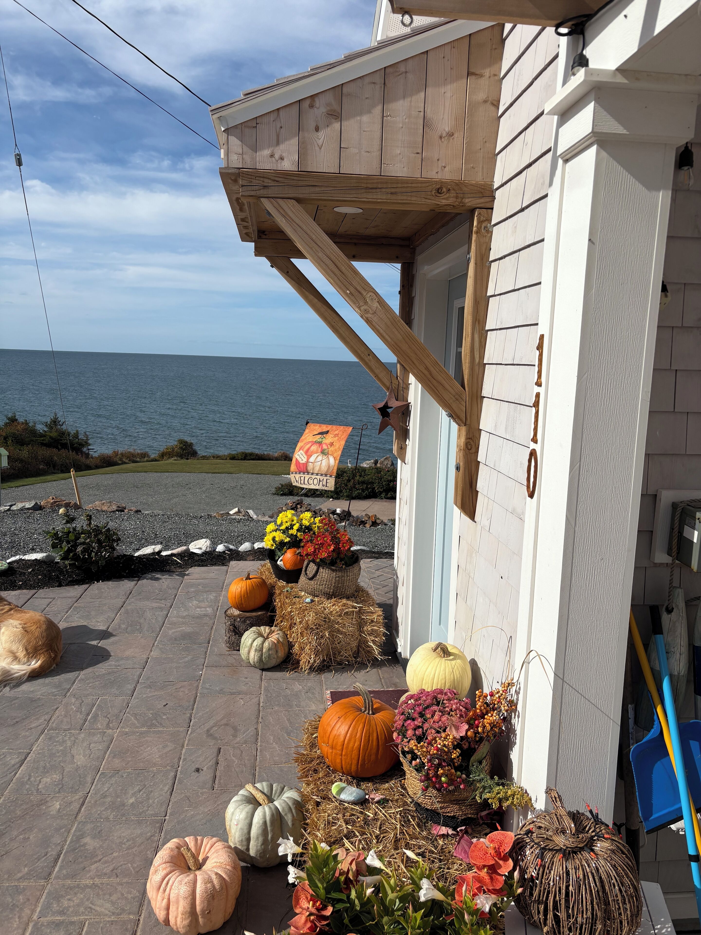 Un bâtiment situé sur la côte, doté d’un porche en bois, d’une enseigne accueillante et de diverses décorations de saison, notamment des citrouilles et des fleurs.