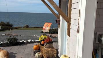 Un bâtiment situé sur la côte, doté d’un porche en bois, d’une enseigne accueillante et de diverses décorations de saison, notamment des citrouilles et des fleurs.