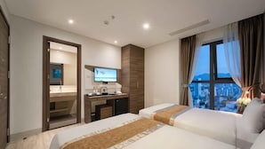 A hotel room with two beds, a desk with a computer, a TV, and a city view. - Zenia Boutique Hotel Nha Trang (Nha Trang)