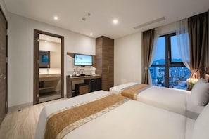 Ett hotellrum med två sängar, ett skrivbord med en dator, en TV och utsikt över staden.