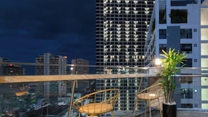 A rooftop terrace with two wicker chairs and a potted plant, overlooking a cityscape at night. - Zenia Boutique Hotel Nha Trang (Nha Trang)