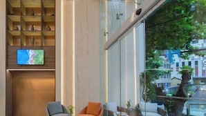 A modern lobby with a glass wall, a map on the wall, and seating areas. - Zenia Boutique Hotel Nha Trang (Nha Trang)