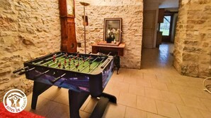 A room with a foosball table, a wooden clock, and a mirror on a shelf.