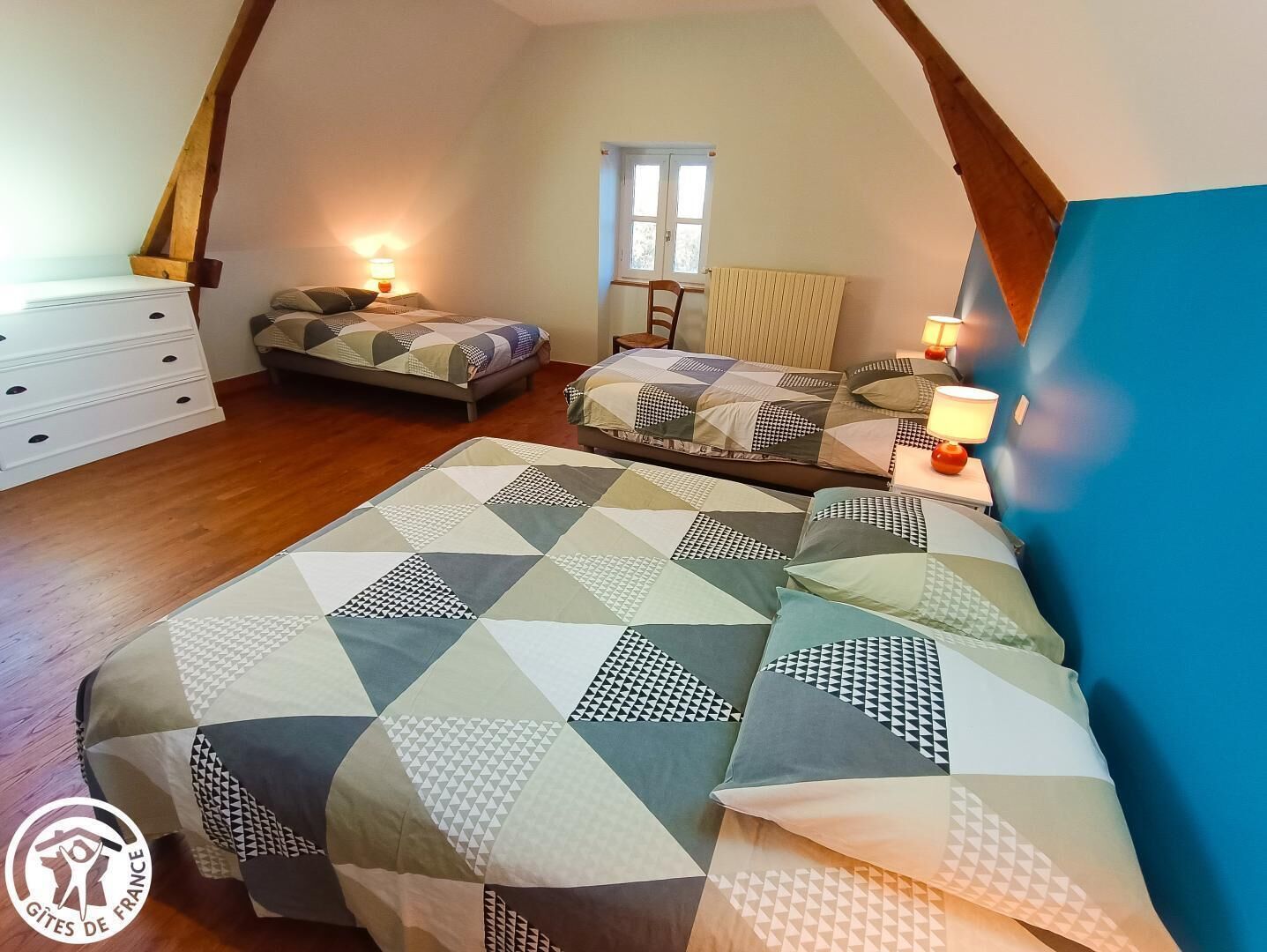 Un dormitorio con dos camas, un aparador, una ventana y un radiador.