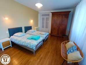 Un dormitorio con dos camas, un armario, una silla y una mesita de noche.