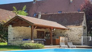 Un edificio de piedra con piscina, terraza cubierta y zona de bar.