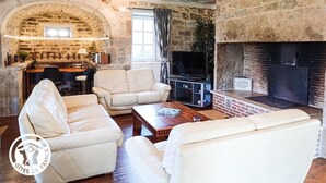Una sala de estar acogedora con paredes de piedra, una chimenea, sofás de cuero y un televisor.