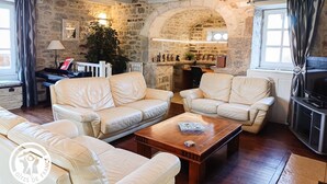 Una sala de estar acogedora con paredes de piedra, un piano y un televisor.