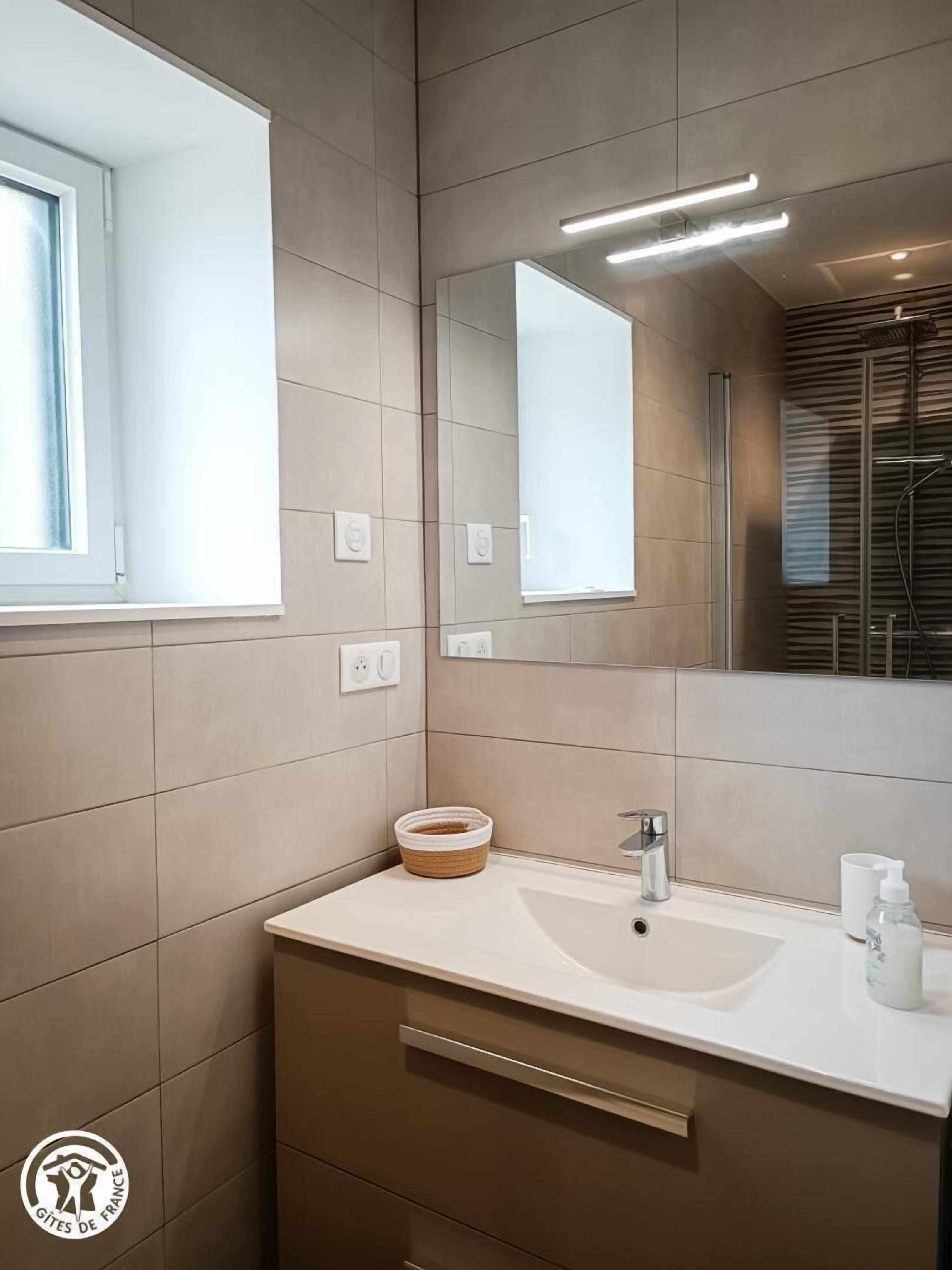 Une salle de bain moderne avec un grand miroir, un lavabo et une fenêtre.