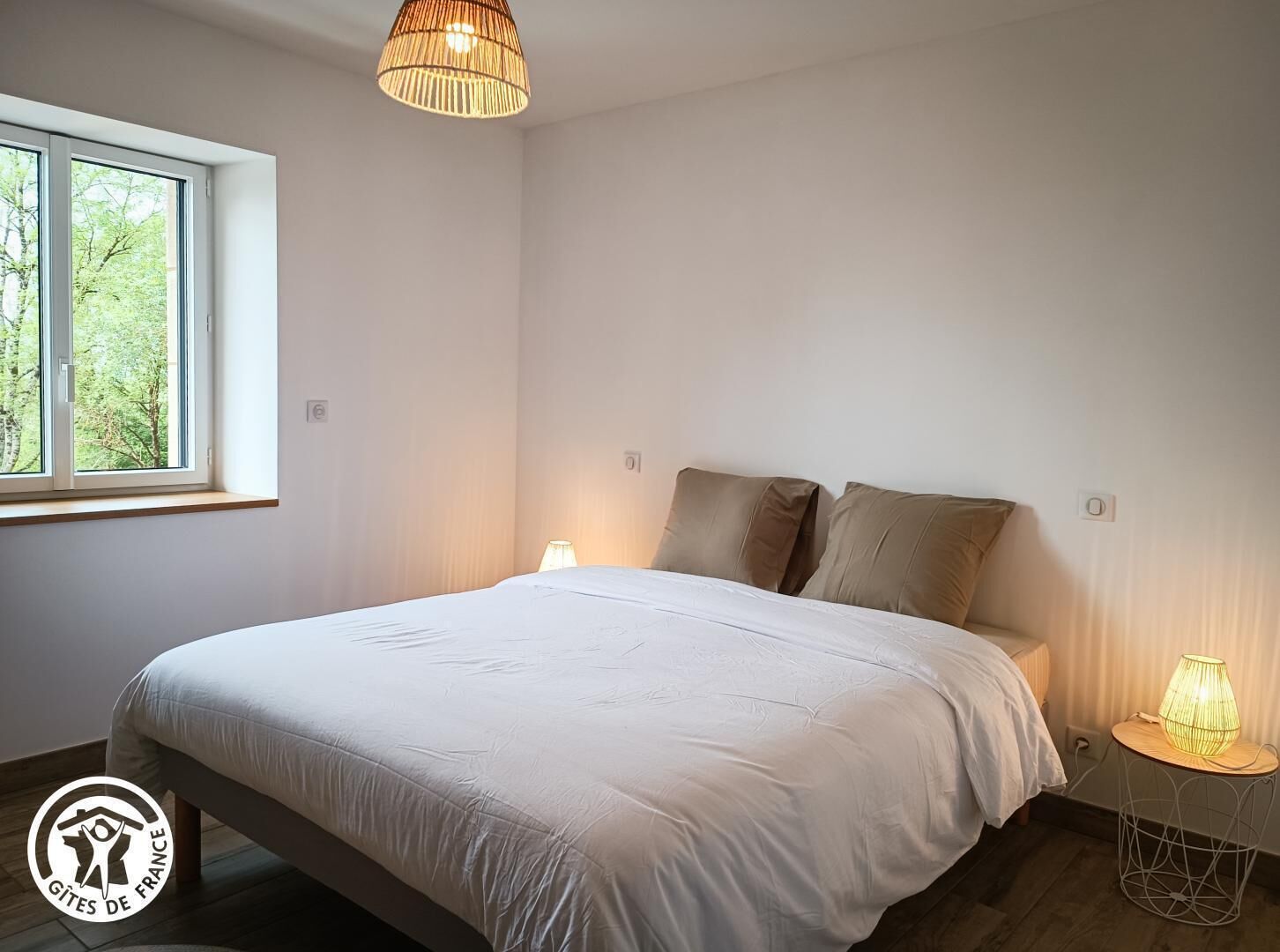 A bedroom with a bed, a window, and a hanging light fixture.