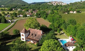 Una casa rural con piscina, rodeada de campos y árboles.