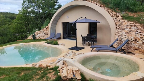 A modern villa with a swimming pool, outdoor seating, and a stone wall. - Gîtes de France® - VIP REFUGE (LE VIGNON-EN-QUERCY)