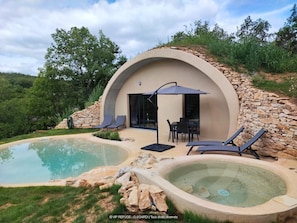 A modern villa with a swimming pool, outdoor seating, and a stone wall. - Gîtes de France® - VIP REFUGE (LE VIGNON-EN-QUERCY)