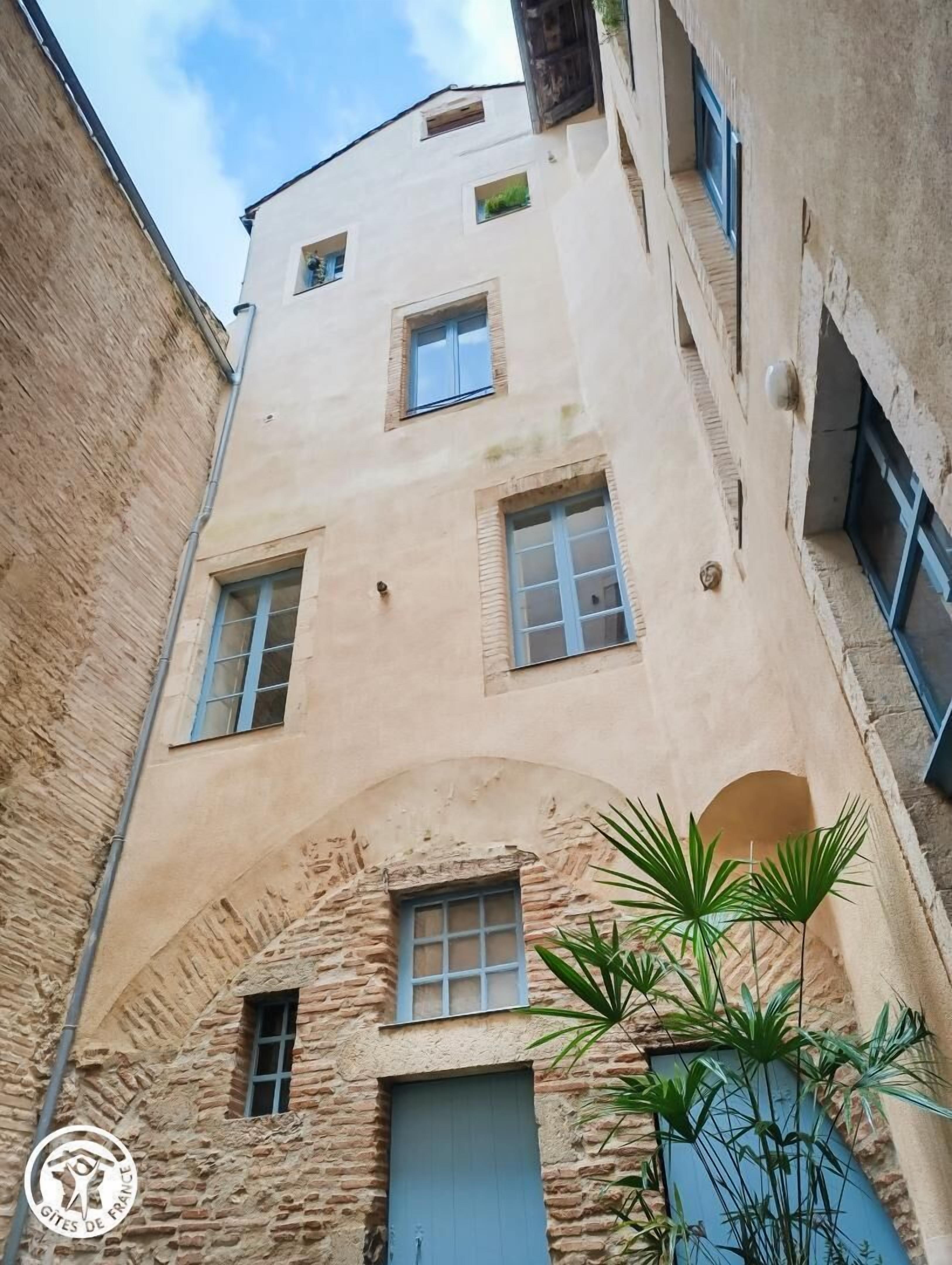 A narrow alleyway with a building featuring multiple windows and a stone archway.