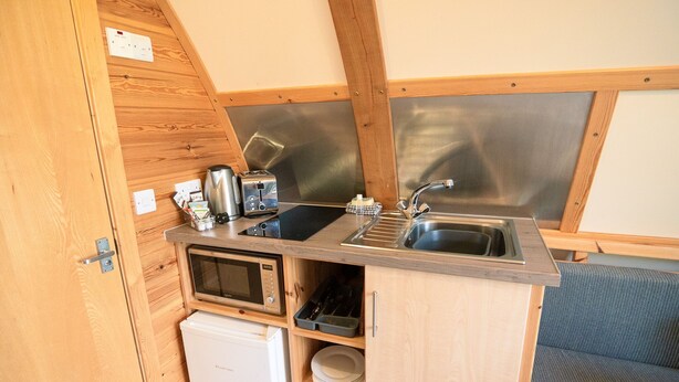 A compact kitchenette with a microwave, toaster, sink, and storage cabinets. - Cosy En-suite Cabin in Moray Speyside (Kinloss)
