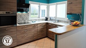 A modern kitchen with a built-in oven, a window, and a fruit bowl on the counter.