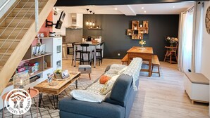 A modern living space with a staircase, a kitchen, a dining area, and a seating area with a sofa and a bench. - Gîtes de France® - La Pèira (LATRONQUIERE)