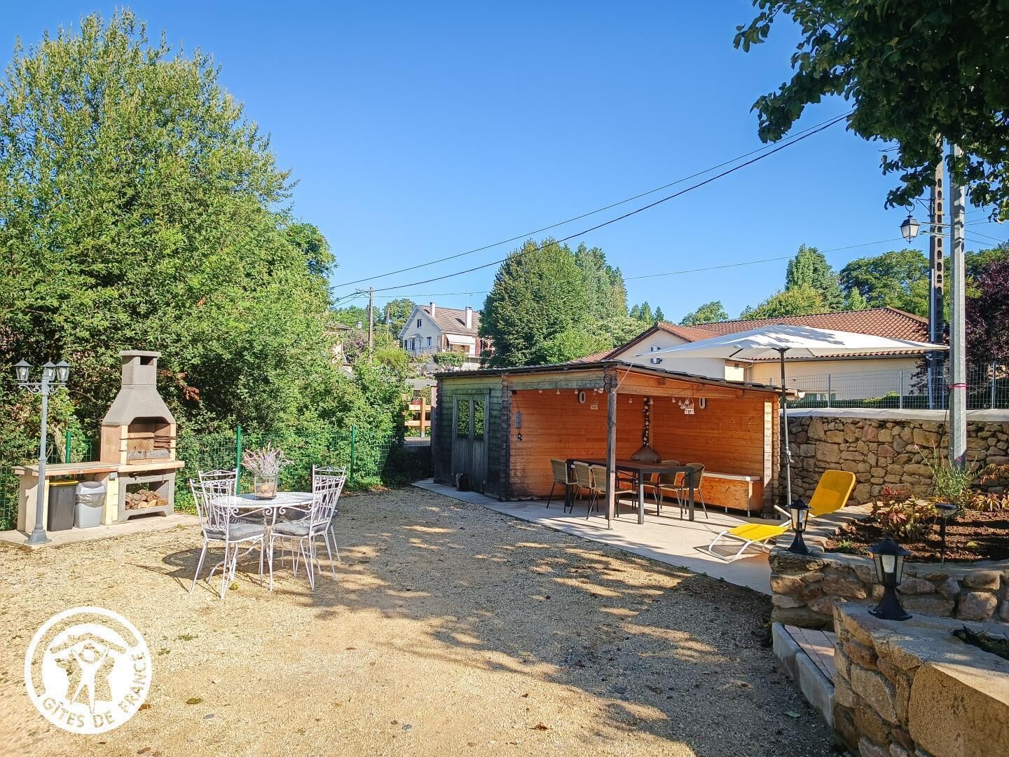A backyard with a barbecue grill, outdoor seating, and a stone wall.