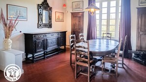 Un comedor con una mesa redonda y sillas, un aparador de madera y un espejo grande en la pared.