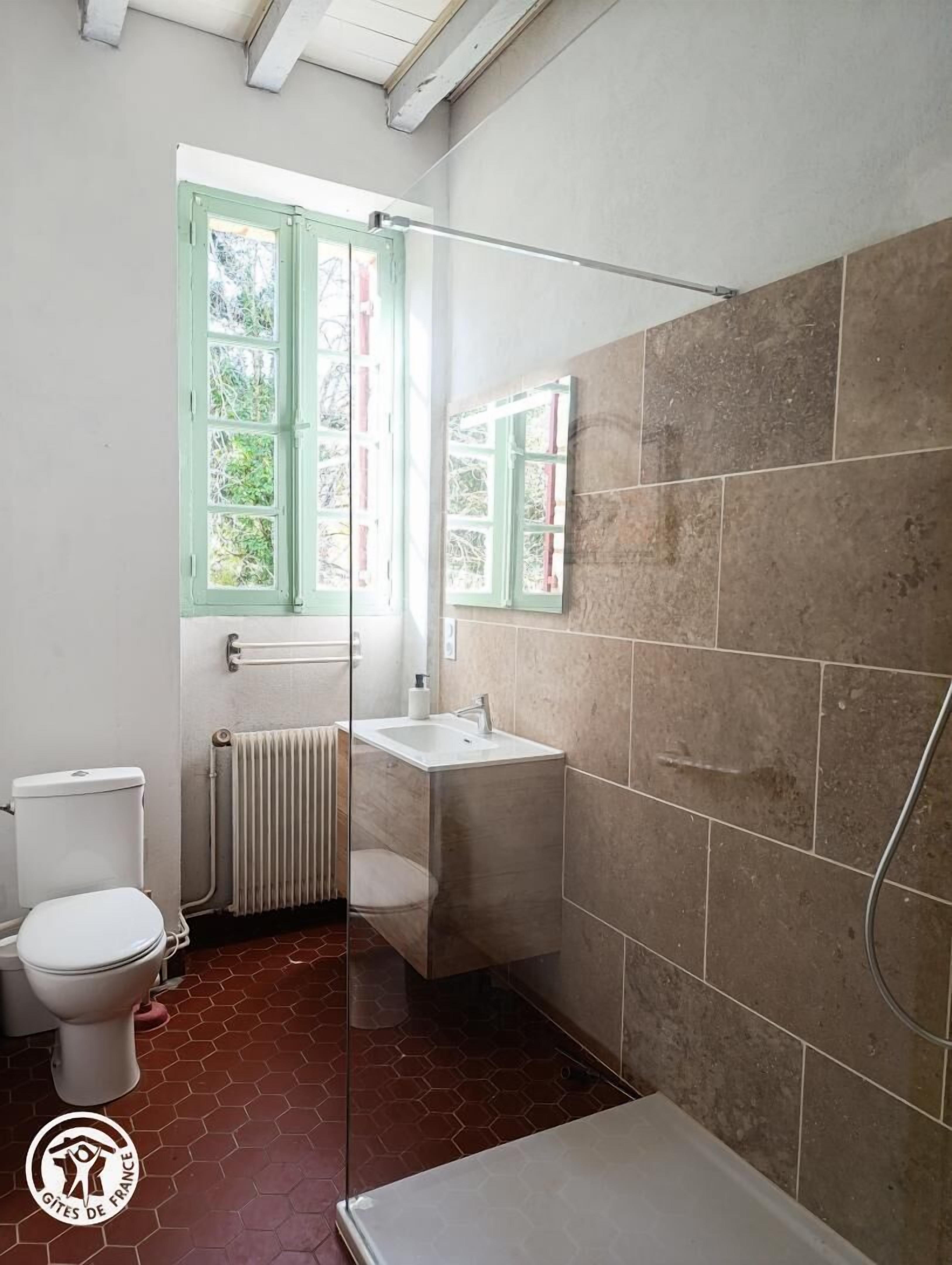 A bathroom with a toilet, a sink, and a shower area.
