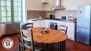 Una cocina compacta con armarios blancos, una mesa de comedor de madera y un horno empotrado.
