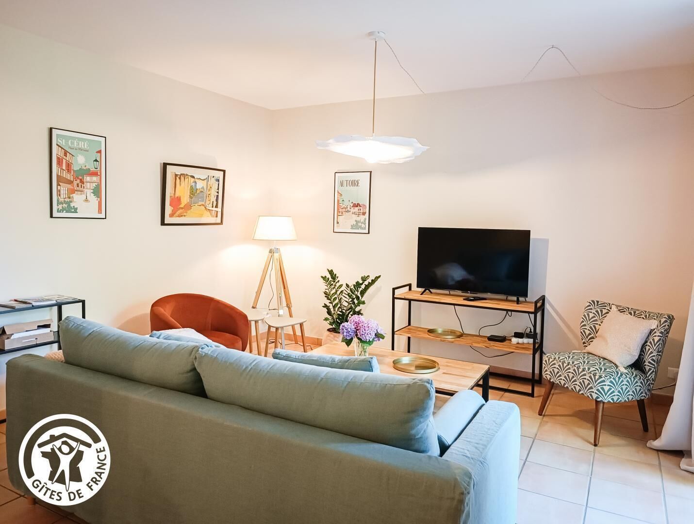 A living room with a sofa, a TV, a lamp, and framed pictures on the wall.