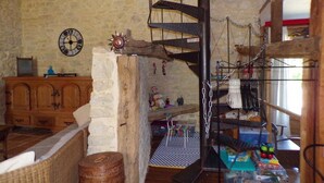 Een rustieke kamer met een wenteltrap, een houten kast en een klok aan de muur.