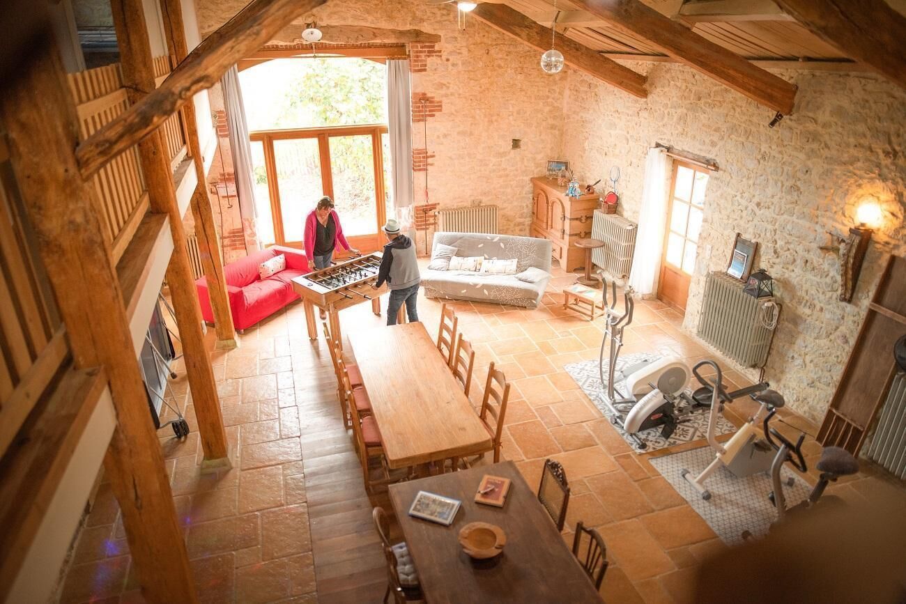 A rustic interior with a wooden dining table, a red sofa, and exercise equipment.