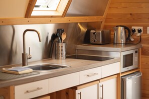 A compact kitchen with a sink, toaster, kettle, and microwave.