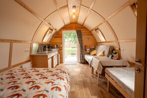 Una habitación acogedora y compacta con una cama, un escritorio pequeño, una mesa y un ventanal.