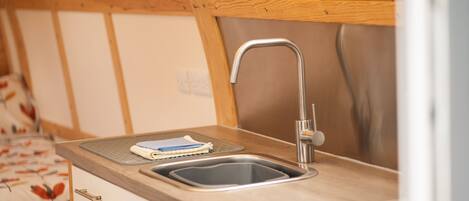 A kitchen with a wooden countertop, a stainless steel sink, and a window above the sink.