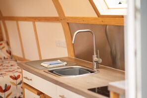 A kitchen with a wooden countertop, a stainless steel sink, and a window above the sink.