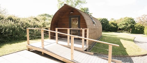 A wooden cabin with a wooden deck and a small porch.