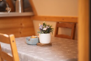 A dining table with a white vase of flowers, a basket, and a wooden chair.