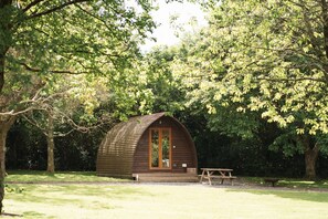 A small wooden cabin with a porch, surrounded by trees. - Cosy En-suite Wigwam Glamping Pod (Tenby)