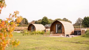A row of wooden cabins with curved roofs, each featuring a door and a small porch area.