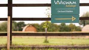 A sign for Wigwam Holidays' Orchard Stables with an arrow pointing to the right.