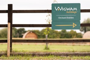 Schild für Wigwam Holidays Orchard Stables, ein Pfeil zeigt nach rechts.