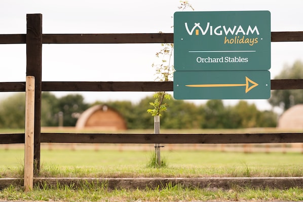 A sign for Wigwam Holidays' Orchard Stables with an arrow pointing to the right.
