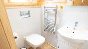 A compact bathroom with a toilet, sink, and towel rack.
