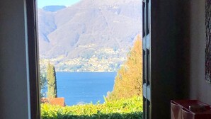 A doorway leading to a balcony with a view of a body of water and mountains. - Mirabella villa with pool and garden  in Brezzo di (Brezzo di Bedero)