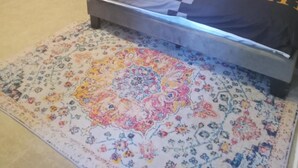 Een slaapkamer met een bed, een bloemenkleed en een schilderij aan de muur.