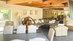 A spacious living room with a large sectional sofa, a wooden ceiling, and a view of the outdoors.